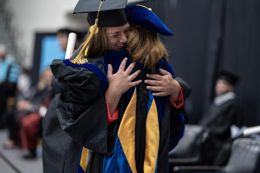 President Dr. Natalie Harder hugs a student at graduation.